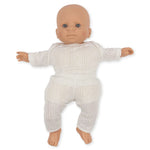 Alfie the Doll, by Konges Slojd, with blue eyes and dressed in a white knitted outfit made from organic cotton, lies peacefully on a plain white surface.