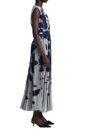 A person in an Altuzarra Pamela dress, a sleeveless pleated midi with a blue and gray abstract pattern similar to a sycamore ladybug print, paired with black heels.