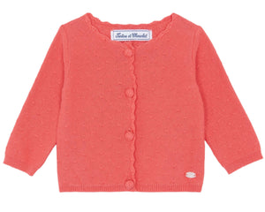 The Baby Girls' Pointelle Cardigan by Tartine et Chocolat is a coral pink knitwear piece with long sleeves, button closure, and a charming scalloped neckline.