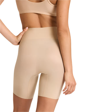 Model wearing Commando Zone Smoothing Shorts, a nude seamless high-waisted compression undergarment, shown from the back with one hand on hip.