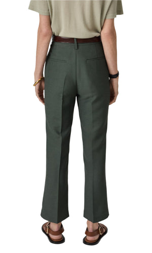 A person stands in CO's Cropped Flared Pant, paired with sandals, showcasing a relaxed yet polished style completed by their tan shirt and brown belt.