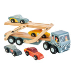 The Tender Leaf Toys Car Transporter features a detachable carrier that holds two super cars on ramps, with three extra toy cars displayed in front of the truck.