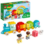 The LEGO® DUPLO® Number Train - Learn To Count is a colorful train with blocks 0–9, two child figures, a white dog, and packaging showing this fun toddler educational toy with a cheerful rainbow illustration.