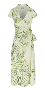 The Mara Dress by Bernadette is a light green wrap dress with an olive tree and floral pattern, short sleeves, side tie waist, V-neckline, and calf-length hem with a charming side-knot detail.