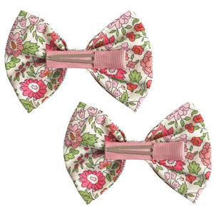 Set of two Milledeux Girls' Large Bowtie Bows in Liberty D’Anjo C fabric with pink, green, and red floral patterns, each featuring a pink clip on the back.