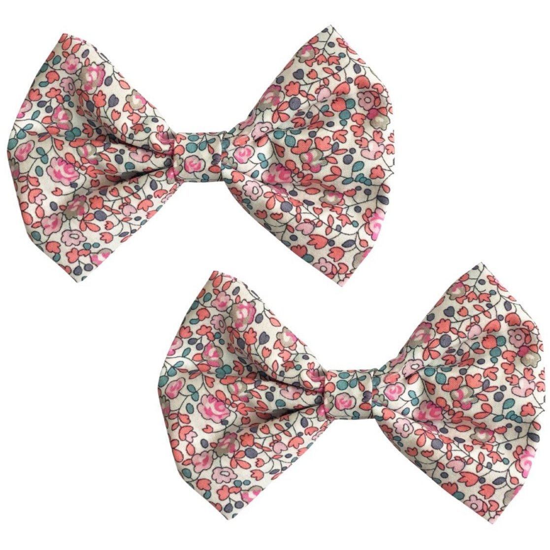 Two Milledeux Girls' Large Bowtie Bows in Liberty Eloise C fabric, featuring a pink, red, and green floral pattern on a light background, are positioned side by side.