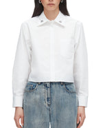 A person wears the 3.1 Phillip Lim Cropped Shirt with Embroidered Collar, featuring a chest pocket, styled with blue jeans.