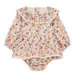 The Louise Misha Baby Girls' India Romper features long sleeves, delicate lace edges, a ruffle collar, and a multicolored floral print on a cream background.