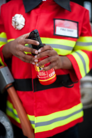 Dressed in the Great Pretenders Firefighter with Accessories Set, an individual embodies the spirit of adventure and safety. With a small fire extinguisher in hand, they are perfectly equipped for any dress-up-and-play scenario, bravely preparing to tackle pretend fires with enthusiasm and care.
