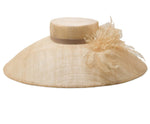The Flora Sinamay Hat by Gigi Burris is a wide-brimmed beige accessory showcasing exquisite millinery techniques, adorned with a chic ribbon band and elegant Flora Sinamay flower decoration.