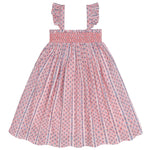 The Minnow Girls' Floral Tile Smocked Dress features a pink and white floral pattern, flutter sleeves, and ruffled shoulder straps, shown against a white background.