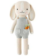 Henry the Bunny by Cuddle + Kind is a 20" knitted stuffed bunny in gray overalls with two small knit carrots in the front pocket, perfect for carrot lovers. Shown against a white background.