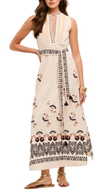 A woman wearing the Figue Joan Dress, a sleeveless cream maxi with embroidered patterns and a belted waist, paired with gold sandals.