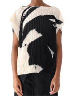 The individual wears a Jason Wu Collection Boatneck Pleated Square Top with a black and white abstract pattern, resembling Tong Yang Tze artwork, paired effortlessly with sleek black pants.