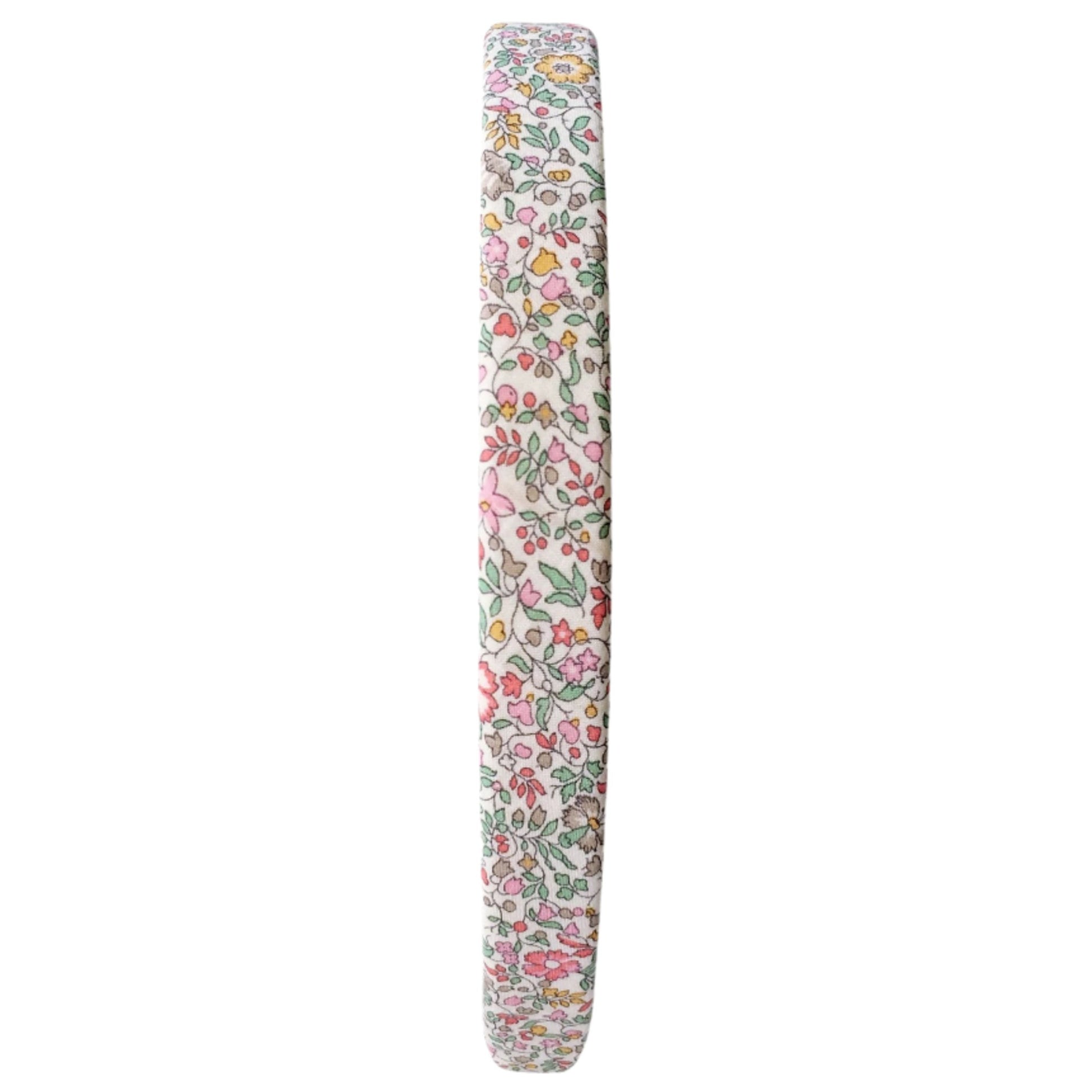 A side-view of the Girls' Medium Plain Hairband by Milledeux reveals pink, green, and yellow flowers on white Liberty Katie & Millie B fabric, blending charm and elegance effortlessly.