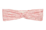 The Julie Headband by Louise Misha is a light pink cotton batiste turban with a delicate floral pattern and stylish front twist, shown laid flat on a white background.