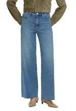 A person wears the Frame Le Slim Palazzo high-rise, wide-leg flare blue jeans, a khaki jacket, and taupe heeled shoes. The upper body and face are not shown.