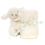 Next to a rolled cream blanket tied with a "Baby Jellycat" ribbon, crafted from recycled fibers, sits a plush Bashful Lamb Soother by Jellycat.