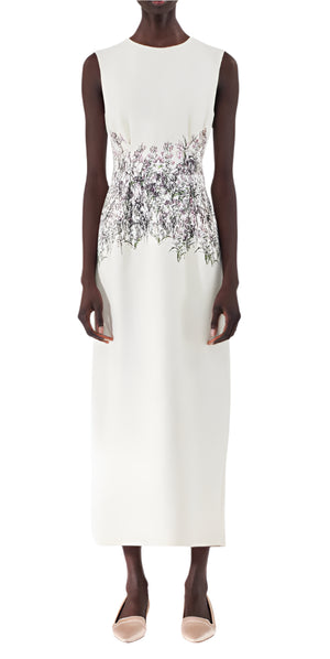 A person wearing the Adam Lippes Ophelia Silk Wool Dress, a sleeveless, ankle-length design in ivory, featuring floral embroidery at the waist, paired with beige shoes.