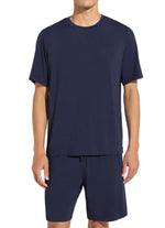 Someone is wearing the Henry Short PJ Set by Eberjey, featuring a navy blue short-sleeve T-shirt and matching shorts made from temperature-regulating TENCEL™ Modal, set against a plain white background.