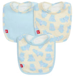 The Pudgemuffin Modal Bib 3-Pack by Magnetic Me features two cream bibs with a blue hippo print and one solid light blue bib, each finished with a red logo tag on the side.