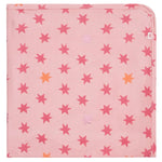 The Cosmic Confetti Baby Blanket by Magnetic Me is a pink square stroller blanket with red, orange, and light pink stars, one rounded corner, and a white tag—made from temperature-regulating fabric for your baby’s comfort.