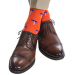 Dapper Classics' Cork Screw Mid Calf Socks, in Tigerlily Orange and Clematis Blue, feature blue and white umbrella patterns. They pair well with brown leather dress shoes for added durability when worn with breathable beige pants.