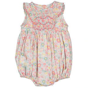 The Antoinette Baby Girls' Marguerite Floral Pink Frilled Sleeveless Smocked Romper features pastel hues, hand-smocked floral embroidery, ruffled shoulders, and elastic leg openings, exemplifying French craftsmanship.