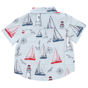 The Boys' Jack Shirt by Pink Chicken is a short-sleeve white shirt with a navy and red nautical print—sailboats, lighthouses, anchors, compasses, and seagulls—ideal for kids who love water adventures.