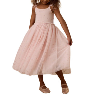 A young girl gracefully poses against a white background in Noralee's Girls' Poppy Dress, featuring a pink sleeveless design with a full tulle skirt and matching ballet flats.