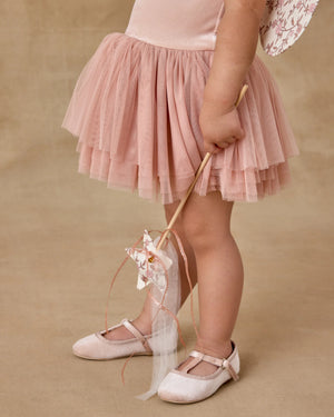 A young child wears the Noralee Tallulah Tutu in pink, paired with matching shoes, and holds a ribbon wand against a neutral background.