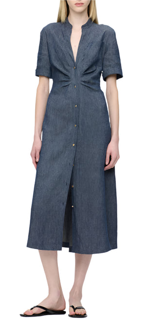 A person wearing the Noor Dress, a flattering fit and flare shirt dress by Callas Milano with short sleeves, paired with black flip-flops.