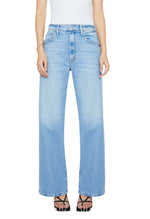 A person wears the MOTHER PETITES The Lil Lasso Sneak light blue high-waisted wide-leg jeans with a white sleeveless top and black strappy heels, standing against a white background.