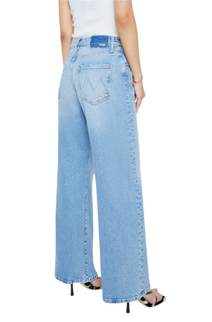 A person wearing light blue PETITES The Lil Lasso Sneak jeans by Mother and a white sleeveless top, seen from the back. The jeans feature back pockets and a leather patch on the waistband.