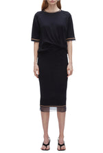 A woman wears the 3.1 Phillip Lim French Tuck Knit Dress with Organza, a black merino blend dress with mesh-trim hem, styled with a French tuck and paired with black heeled sandals.