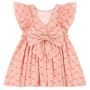 The Konges Slojd Girls' Ava Bow Dress features a pink and cream pattern, soft cotton fabric, ruffled sleeves, frill details, and a large front bow, shown against a white background.