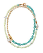 The Cabana Necklace by Lizzie Fortunato features strands of turquoise, beige, and light green color-blocked beads, accented with gold details and irregular white pearls.