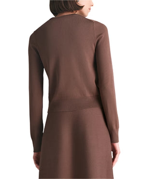 A woman is shown from the back wearing the Lela Rose Raffia Embroidered Knit Long Sleeve Cardigan with a matching skirt, both in brown cozy knit, set against a white background.