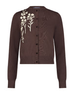 The Lela Rose Raffia Embroidered Knit Long Sleeve Cardigan features front buttons and white floral embroidery on soft brown knit.