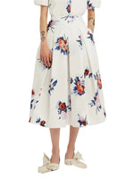 Someone dressed in Erdem's Painted Rose Bouquet Pleated Midi Skirt—a white, floral-print, knee-length cotton poplin A-line skirt—paired with a white top and cream bow shoes.