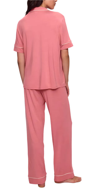 An individual is shown barefoot, facing away, wearing the Gisele Short Sleeve Long Pant PJ Set in pink with contrast piping by Eberjey.