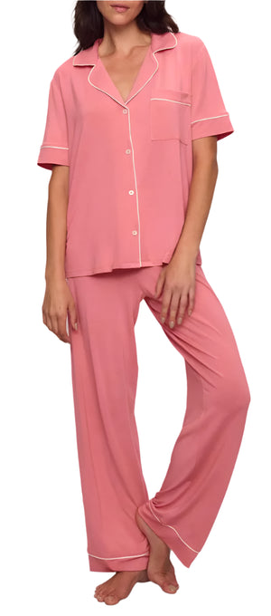 A person is barefoot against a white background, wearing Eberjey's Gisele Short Sleeve Long Pant PJ Set in pink, featuring a classic fit top with short sleeves, contrast piping, and elastic waistband pants.
