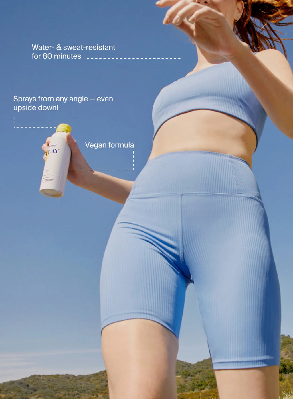 A woman in a blue sports outfit holds Supergoop Play Antioxidant Mist SPF 50 with Vitamin C, 6 fl oz, outdoors, with text highlighting water resistance, 360° sprayability, and a vegan formula for radiant skin.