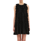 A woman wearing the Ulla Johnson Signe Mini Dress, a sleeveless silk style with cascading ruffles, stands against a white background.