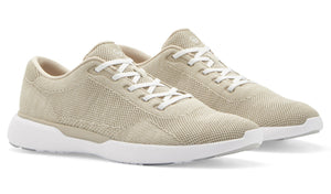 A pair of Peter Millar's Glide V3 sneakers in light beige, showcasing a textured fabric design with white laces and herringbone traction white soles, set against a white background.