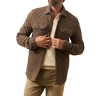 A man wears the Faherty Epic Quilted Fleece jacket over a cream shirt, tan pants, and brown shoes, standing against a white background.