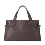 The Staud Piper Tote is a brown leather work bag with two handles, a structured, minimalist design, and subtle buckle accents.