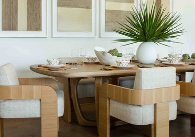 contemporary dining vignette with light wood colored dining chairs, light wood table with neutral table settings, and a green spiky plant on table