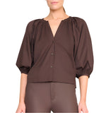 A woman wearing the Staud Dill Top, a dark brown cotton poplin style with puffed three-quarter sleeves, paired with matching brown pants.