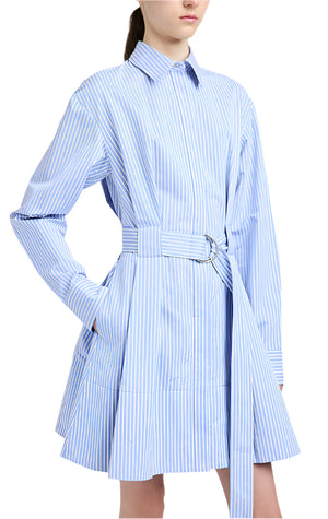 A person wears the Proenza Schouler Viola Dress, crafted in blue and white striped cotton silk poplin, featuring a D-ring belt and pockets.
